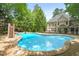 Sparkling pool with slide surrounded by brick patio and lush trees in a private backyard setting at 10540 Byrum Woods Dr, Raleigh, NC 27613