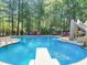 Outdoor pool with a diving board and slide, surrounded by lounge seating and mature trees at 10540 Byrum Woods Dr, Raleigh, NC 27613