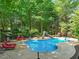 Backyard pool with a slide, shaded lounge chairs, and lush trees create a peaceful setting at 10540 Byrum Woods Dr, Raleigh, NC 27613