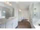 A full bathroom featuring double vanities, wood-look tile floors, and a glass-enclosed shower with marble surround at 109 Obsidian Dr, Holly Springs, NC 27540