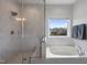 Bright bathroom featuring glass shower, soaking tub, marble-look tiling, and a window with backyard views at 109 Obsidian Dr, Holly Springs, NC 27540