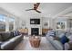 Bright living room with fireplace, hardwood floors, ceiling fan, and dual leather sofas at 109 Obsidian Dr, Holly Springs, NC 27540