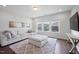Bright living room with plush rug, white sofa, and many windows overlooking the neighborhood at 109 Obsidian Dr, Holly Springs, NC 27540
