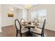 This dining room has hardwood floors, a large window, and a chandelier hanging over a round table set for four at 1104 Arden Trace Ct, Fuquay Varina, NC 27526