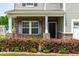 Close up of front porch with stone accents, lovely flowerbed, garden gnomes, and black front door at 1104 Arden Trace Ct, Fuquay Varina, NC 27526