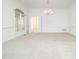 Bright living room featuring neutral carpet, wainscotting, and a decorative chandelier at 11221 Paddy Hollow Ln, Raleigh, NC 27614