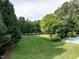 A large, well-manicured backyard featuring a pool surrounded by lush trees offers a private outdoor retreat at 1201 Kalworth Rd, Wake Forest, NC 27587
