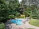 Backyard in-ground pool with stone patio, lounge chairs, umbrellas, and beautiful landscaping for summer fun at 1201 Kalworth Rd, Wake Forest, NC 27587