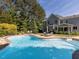 Beautiful in-ground backyard pool with surrounding patio, lounge seating, and mature trees for privacy at 1201 Kalworth Rd, Wake Forest, NC 27587