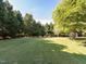 Large grassy backyard with mature trees, landscaping, and space for recreation and activities at 1201 Kalworth Rd, Wake Forest, NC 27587