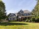 Elegant two-story home featuring stone accents, blue siding, lush landscaping, and a spacious front lawn at 1201 Kalworth Rd, Wake Forest, NC 27587