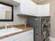 Bright laundry room features modern washer and dryer, spacious counter, storage cabinets, and black framed mirror at 1201 Kalworth Rd, Wake Forest, NC 27587