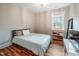 Cozy bedroom with hardwood floors, a simple bed frame, and natural light from a window at 129 E Chestnut Ave, Wake Forest, NC 27587