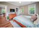 Well-lit bedroom with a queen-sized bed, dresser, and two windows offering natural light at 129 E Chestnut Ave, Wake Forest, NC 27587