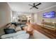 Comfortable living room with hardwood floors, gray sectional sofa, ceiling fan, and flat screen TV at 129 E Chestnut Ave, Wake Forest, NC 27587