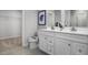 Bright bathroom featuring dual sinks, white cabinetry, modern fixtures, and a walk-in closet at 1424 Rollman Farm Rd, Raleigh, NC 27603