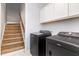 Laundry room showing black washer and dryer next to stairs and cabinets at 174 Tafton Dr, Wendell, NC 27591