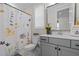 Charming bathroom featuring floral shower curtain, decorative mirror, grey vanity, and natural light at 190 Wendover Pkwy, Pittsboro, NC 27312