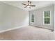 A carpeted bedroom features neutral colored walls, a ceiling fan, and large windows offering an abundance of natural light at 2028 Pleasant Forest Way, Wake Forest, NC 27587