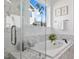 Well-lit tub and shower combo feature marble surround and floors, with a plant next to the window at 204 Woodstaff Ave, Wake Forest, NC 27587