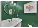 Chic powder room featuring dark green walls, gold accents, a round mirror, and modern artwork at 207 Old Forest Creek Dr, Chapel Hill, NC 27514