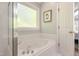 Bright bathroom featuring a soaking tub under a window, adjacent to the door and shower at 213 Birch Creek Dr, Fuquay Varina, NC 27526