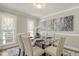 Elegant dining room featuring modern chandelier, large window, glass table and seating for six at 213 Birch Creek Dr, Fuquay Varina, NC 27526