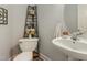 This powder room features a pedestal sink, decorative shelving, and modern fixtures at 213 Birch Creek Dr, Fuquay Varina, NC 27526