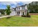 Beautiful white house with black shutters, a covered porch, green lawn and mature trees on a sunny day at 22 Chapman Ct, Wendell, NC 27591