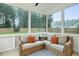 Enclosed sunroom featuring wicker seating with plush cushions and views of the wooded backyard at 22 Chapman Ct, Wendell, NC 27591