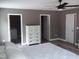 This bedroom features three doors, a ceiling fan, and light colored floors at 249 Fisherman Point Rd, Roxboro, NC 27574