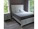 Bright bedroom with a bed and a side table, featuring natural light from two windows at 249 Fisherman Point Rd, Roxboro, NC 27574