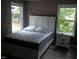 Bright bedroom with a bed and a side table, featuring natural light from two windows at 249 Fisherman Point Rd, Roxboro, NC 27574