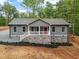 Charming one-story home featuring gray siding, a stone foundation, and a welcoming front porch with a bright red door at 249 Fisherman Point Rd, Roxboro, NC 27574