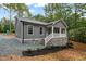 Cozy one-story home featuring gray siding, a stone foundation, and a charming front porch with bright white railings at 249 Fisherman Point Rd, Roxboro, NC 27574