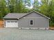Detached garage with gray siding and white garage door, nestled in a wooded area at 249 Fisherman Point Rd, Roxboro, NC 27574