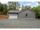 Gray detached garage with a white garage door on a gravel driveway with stone foundation detail at 249 Fisherman Point Rd, Roxboro, NC 27574