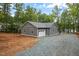 Detached garage with a white door and gray siding situated on a gravel driveway near the lake at 249 Fisherman Point Rd, Roxboro, NC 27574