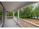 Covered porch with white railings, offering serene views of the wooded landscape and lake at 249 Fisherman Point Rd, Roxboro, NC 27574