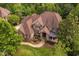 Aerial view of an expansive brick home with mature landscaping, a circular driveway, and water feature at 3601 Nightfall Ct, Raleigh, NC 27607