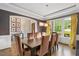 Elegant dining room with a large table, eight chairs, unique lighting, and large window overlooking yard at 3601 Nightfall Ct, Raleigh, NC 27607