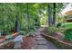 Landscaped backyard with stone path, lush greenery, and a charming stone bench perfect for enjoying nature at 372 Farnleigh Dr, Chapel Hill, NC 27517