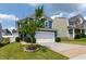 View of home with 2-car garage, blue siding, and a well-maintained lawn with a young tree at 3913 Massey Pointe Ct, Raleigh, NC 27616