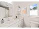 All white bathroom with large mirror, decorated shelves, and a window to the backyard at 4500 Lancashire Dr, Raleigh, NC 27613