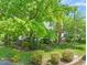 View of home with landscaping, mature trees, and a brick chimney at 4500 Lancashire Dr, Raleigh, NC 27613
