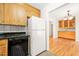 Kitchen with wood cabinets and black countertops next to a white refrigerator, leading into a dining area with hardwood floors at 4500 Lancashire Dr, Raleigh, NC 27613