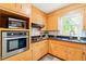 Well-lit kitchen featuring wooden cabinets, granite countertops, stainless steel oven and microwave, and a view of the outdoors at 4500 Lancashire Dr, Raleigh, NC 27613