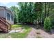 Picturesque backyard features a blend of grass, wooded area, and convenient access to the house via wooden stairs at 4953 Mashpee Ln, Apex, NC 27539