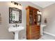 Bathroom featuring dual pedestal sinks, decorative cabinet, and bright natural lighting at 4953 Mashpee Ln, Apex, NC 27539