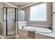 Bright bathroom featuring a soaking tub with tile surround and walk-in shower with glass door at 4953 Mashpee Ln, Apex, NC 27539